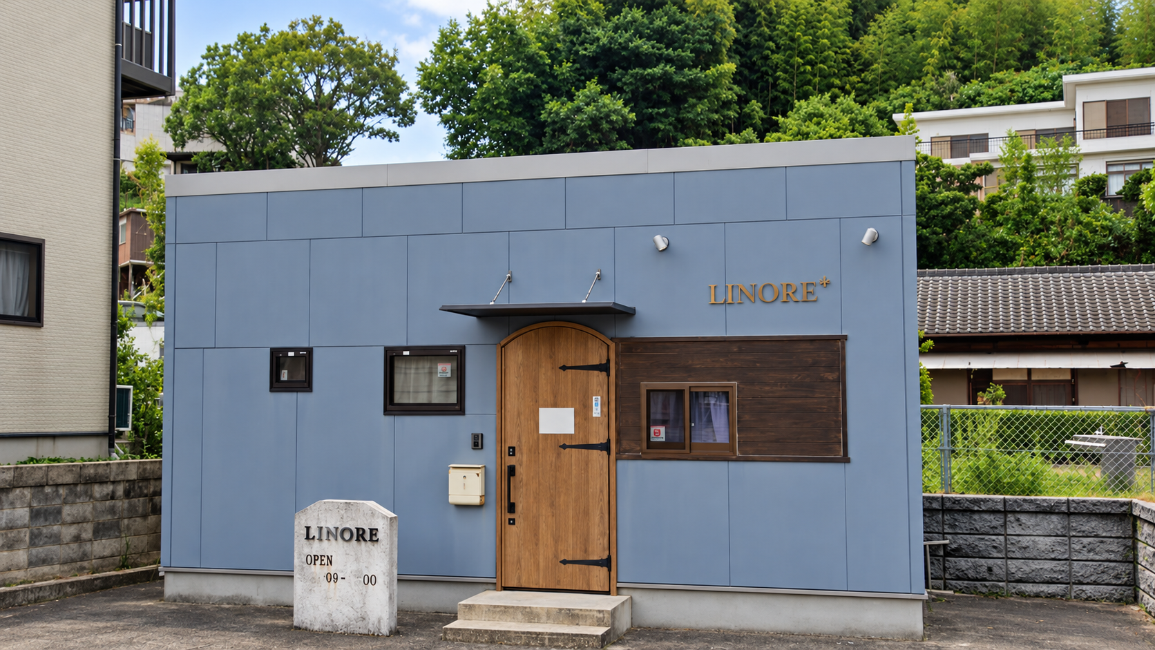 LINORE+の店舗外観。グレーの外壁と木製の入口が目印です。
